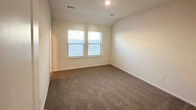 unfurnished room with dark carpet and lofted ceiling