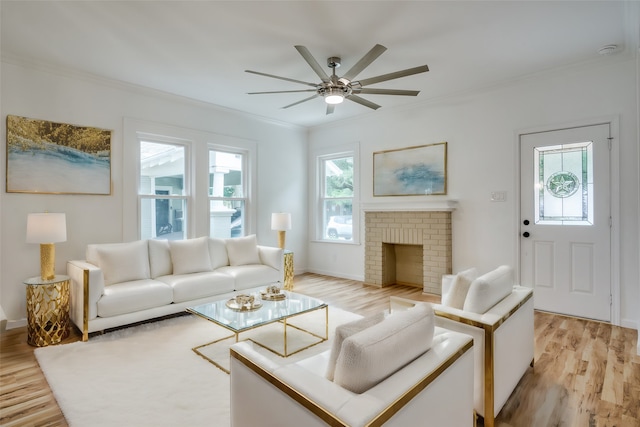 living room featuring ceiling fan, light hardwood / wood-style floors, ornamental molding, and a brick fireplace