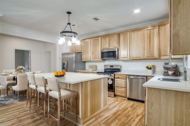 kitchen with sink, a center island, hanging light fixtures, appliances with stainless steel finishes, and ornamental molding