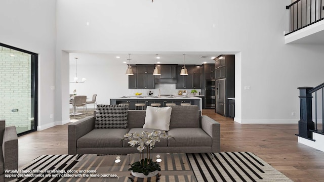 living room featuring a chandelier, a high ceiling, hardwood / wood-style flooring, and a wealth of natural light