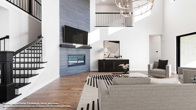 living room with a tiled fireplace, a healthy amount of sunlight, wood-type flooring, and a high ceiling