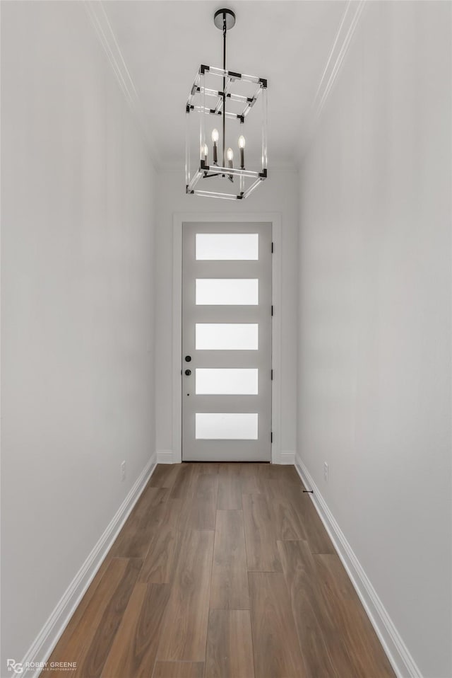 entryway with wood-type flooring, ornamental molding, and an inviting chandelier