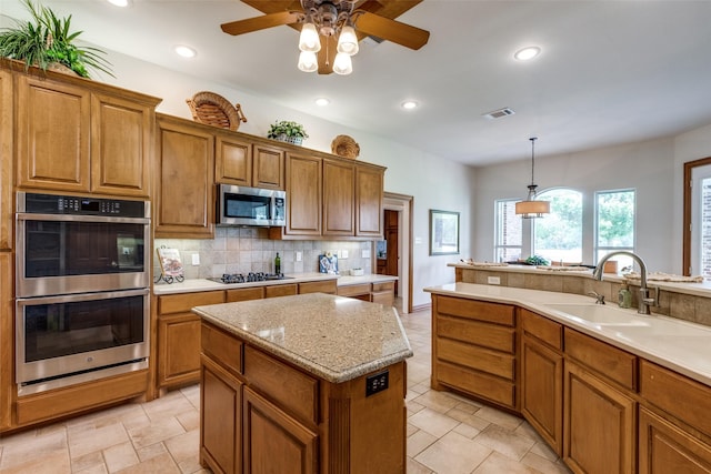 kitchen featuring tasteful backsplash, stainless steel appliances, sink, pendant lighting, and a center island