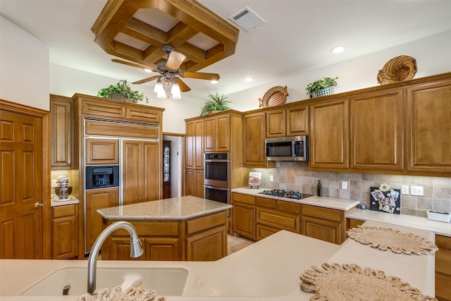 kitchen featuring a center island, backsplash, sink, ceiling fan, and appliances with stainless steel finishes