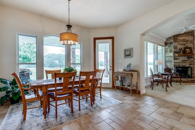 carpeted dining area with ceiling fan and a fireplace