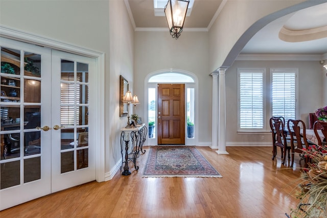 foyer featuring decorative columns, french doors, light hardwood / wood-style floors, and ornamental molding