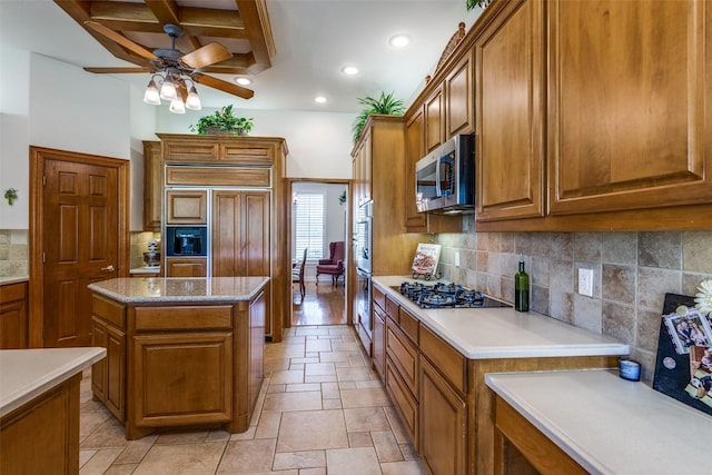 kitchen with appliances with stainless steel finishes, backsplash, ceiling fan, beam ceiling, and a center island