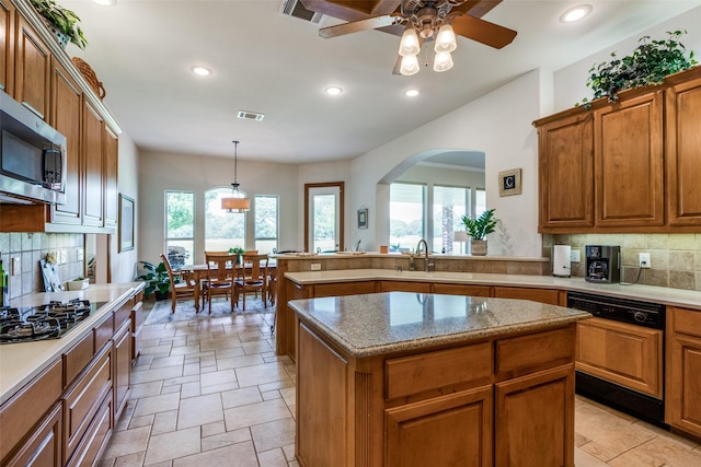 kitchen featuring pendant lighting, backsplash, ceiling fan, a kitchen island, and stainless steel appliances