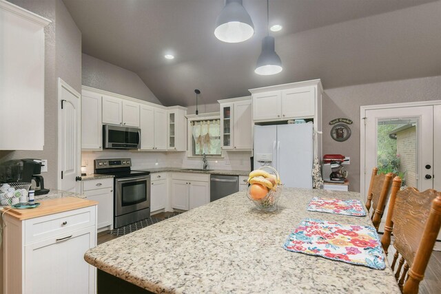 kitchen with white cabinetry, appliances with stainless steel finishes, pendant lighting, decorative backsplash, and lofted ceiling