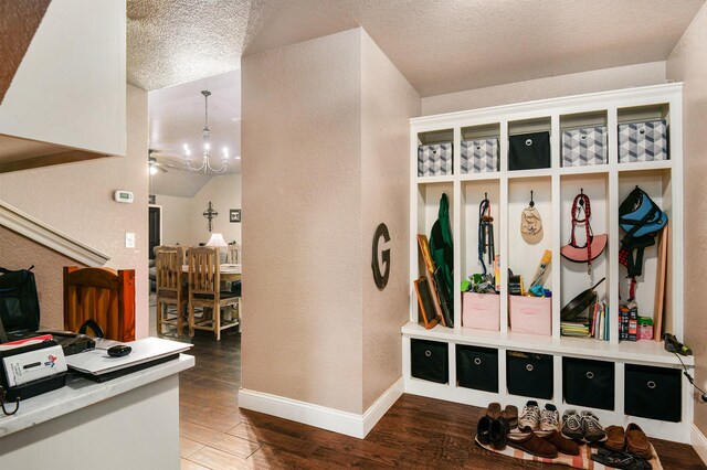 mudroom with an inviting chandelier, dark hardwood / wood-style floors, and a textured ceiling