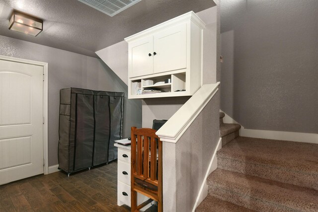 staircase with hardwood / wood-style floors, lofted ceiling, and a textured ceiling