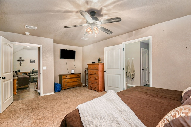 carpeted bedroom featuring ensuite bathroom, a textured ceiling, lofted ceiling, and ceiling fan