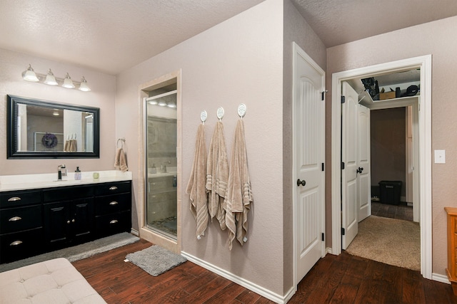 bathroom with wood-type flooring, vanity, a textured ceiling, and a shower with shower door