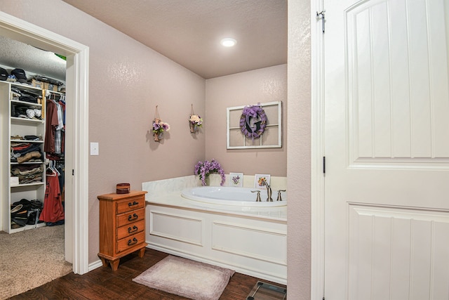 bathroom with a tub, hardwood / wood-style flooring, and a textured ceiling