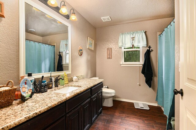 bathroom featuring hardwood / wood-style flooring, vanity, toilet, and a textured ceiling