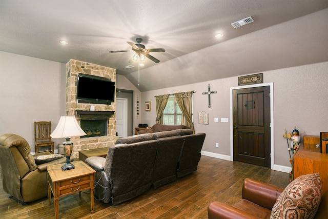 living room featuring a stone fireplace, dark hardwood / wood-style floors, ceiling fan, and vaulted ceiling