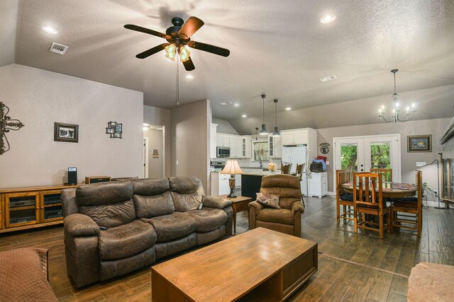 living room with ceiling fan with notable chandelier, a textured ceiling, lofted ceiling, dark wood-type flooring, and french doors