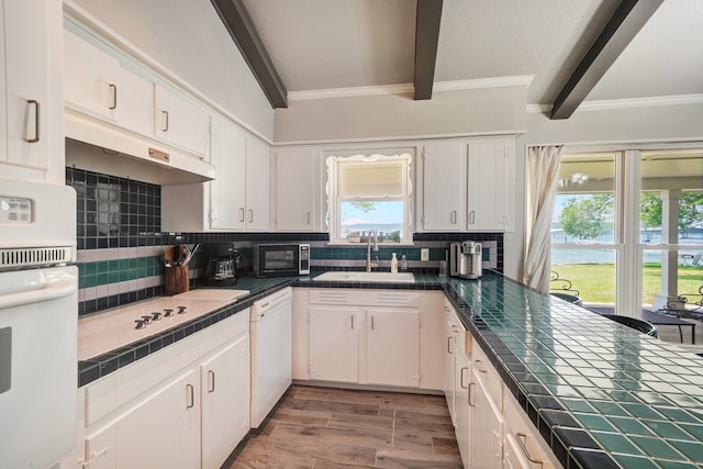 kitchen featuring tile countertops, white appliances, backsplash, white cabinets, and sink