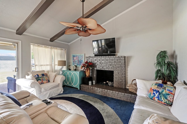 living room featuring carpet flooring, ceiling fan, a brick fireplace, vaulted ceiling with beams, and crown molding