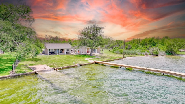 yard at dusk featuring a water view