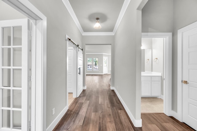 hall featuring a barn door, crown molding, and dark wood-type flooring