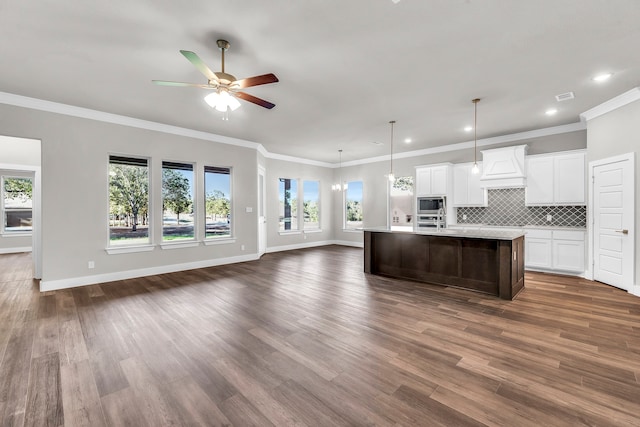 kitchen with white cabinets, dark hardwood / wood-style flooring, a center island with sink, and plenty of natural light