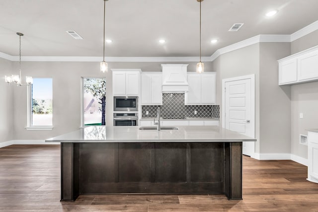 kitchen featuring stainless steel appliances, hanging light fixtures, sink, and a spacious island