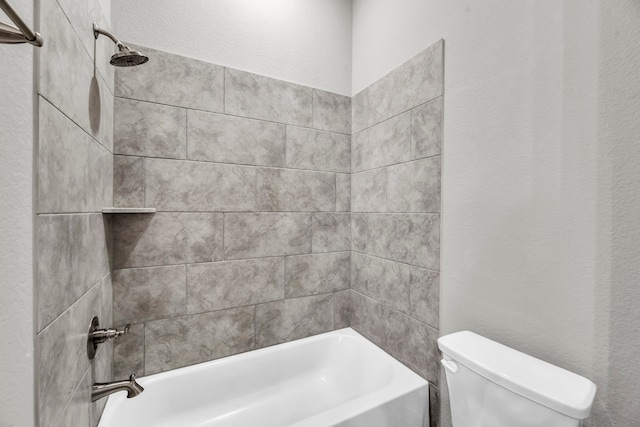 bathroom featuring tiled shower / bath combo and toilet