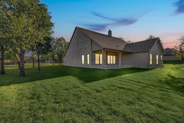 property exterior at dusk featuring a lawn