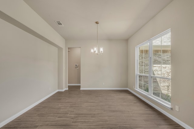 unfurnished room featuring a notable chandelier, light hardwood / wood-style flooring, and plenty of natural light