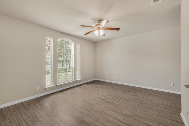 unfurnished room featuring dark wood-type flooring, ceiling fan, and a wealth of natural light