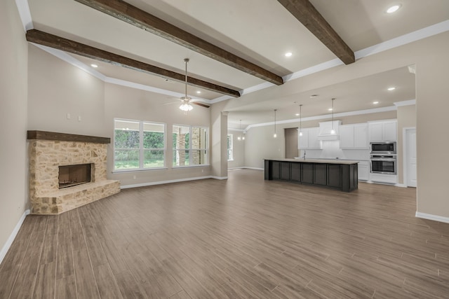 unfurnished living room featuring a stone fireplace, hardwood / wood-style floors, and ceiling fan