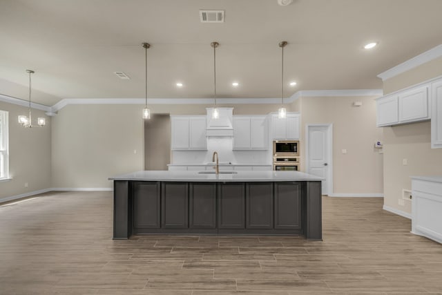 kitchen with appliances with stainless steel finishes, a kitchen island with sink, and white cabinetry