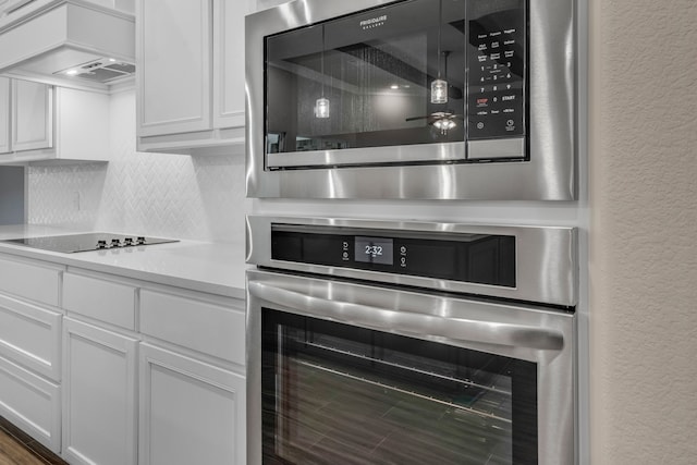 kitchen featuring premium range hood, tasteful backsplash, white cabinetry, stainless steel appliances, and dark hardwood / wood-style floors