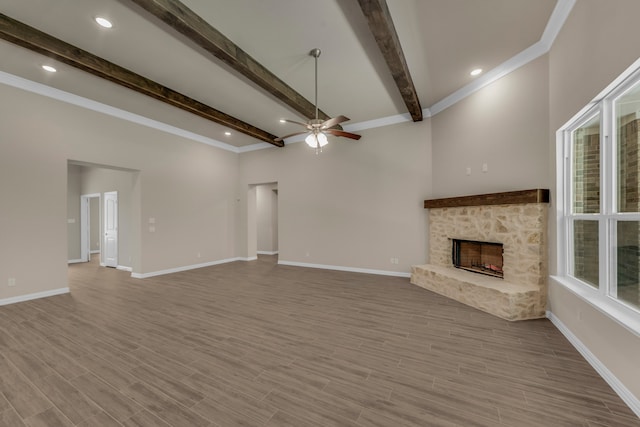 unfurnished living room featuring ceiling fan, light wood-type flooring, a fireplace, and beam ceiling