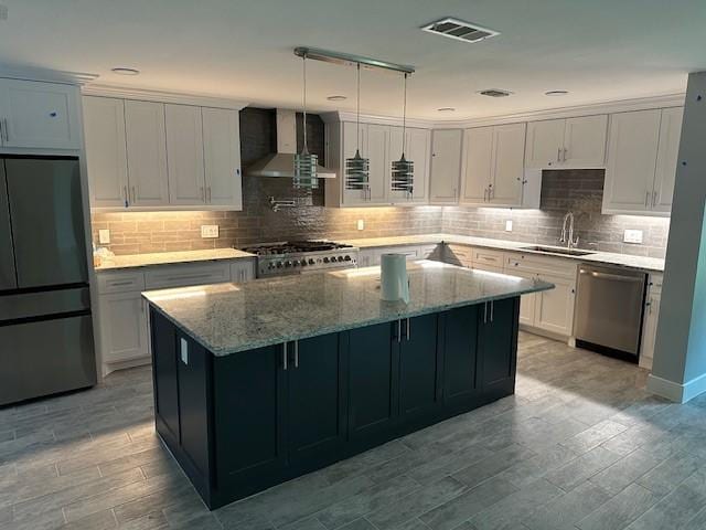 kitchen featuring a kitchen island, decorative light fixtures, wall chimney range hood, fridge, and stainless steel dishwasher