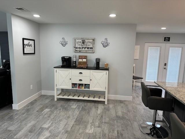 bar with wood-type flooring and french doors