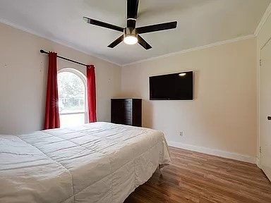 bedroom featuring ceiling fan, ornamental molding, and hardwood / wood-style flooring