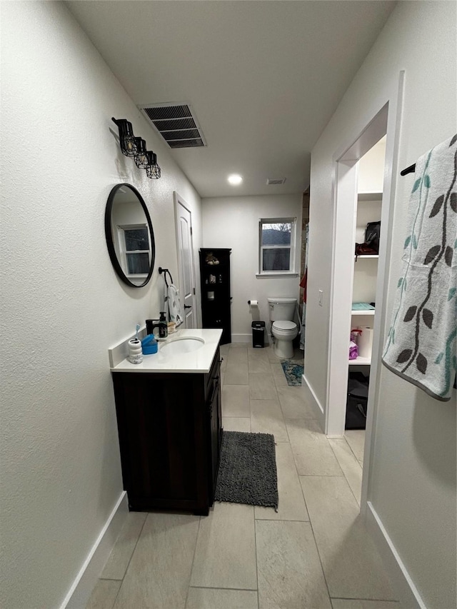 bathroom with toilet, vanity, and tile patterned flooring