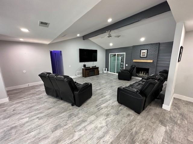 living room with ceiling fan, lofted ceiling with beams, a fireplace, and light hardwood / wood-style floors