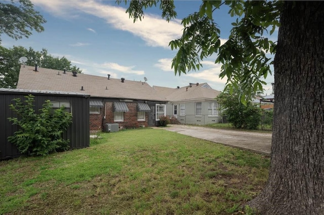 back of house with a yard and central AC