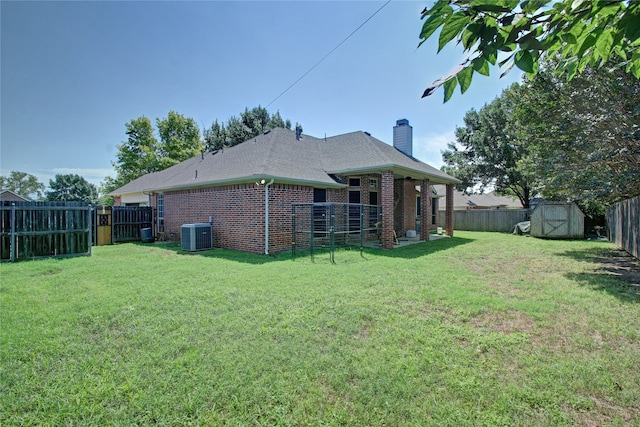 back of house featuring a lawn, a storage shed, and central AC unit