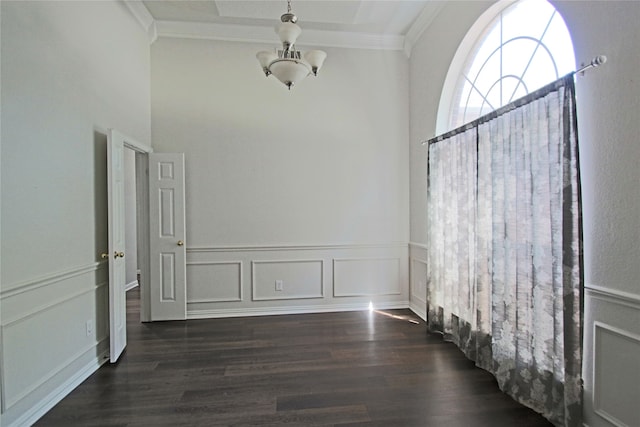 empty room featuring crown molding, dark hardwood / wood-style flooring, and a chandelier