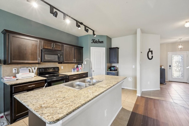 kitchen featuring black appliances, tasteful backsplash, sink, dark brown cabinetry, and an island with sink