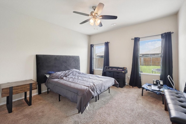 carpeted bedroom featuring multiple windows and ceiling fan