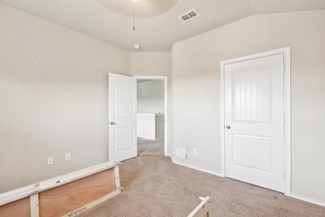 unfurnished bedroom featuring light carpet and vaulted ceiling