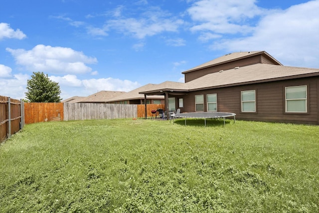 back of property featuring a trampoline and a lawn