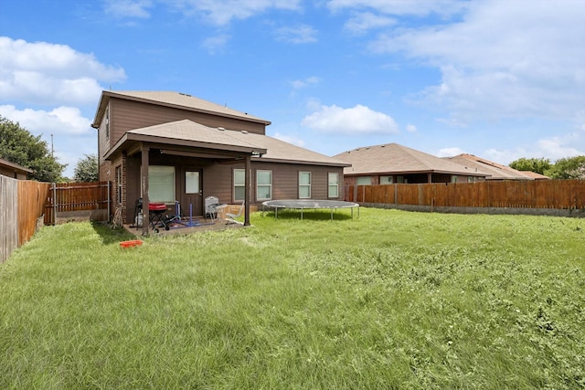 rear view of property featuring a trampoline and a yard