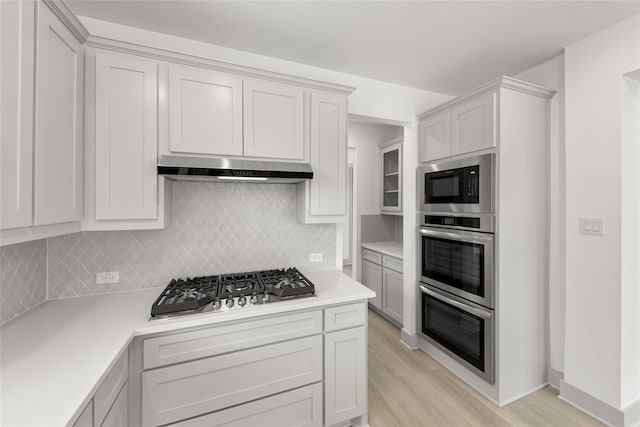 kitchen featuring white cabinets, stainless steel appliances, light hardwood / wood-style floors, and tasteful backsplash