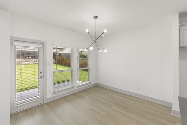 unfurnished dining area featuring a notable chandelier and light hardwood / wood-style floors